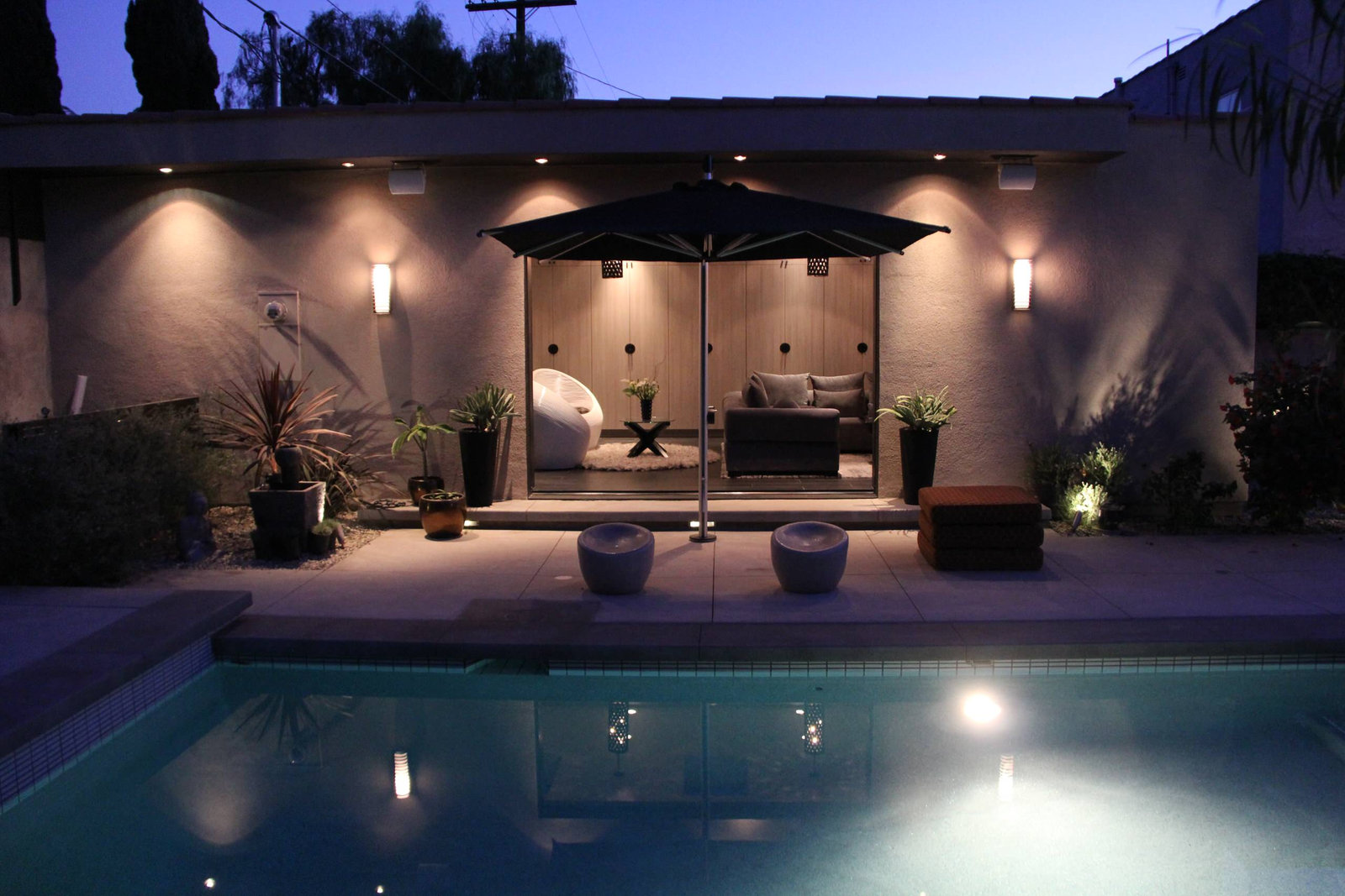 Modern ADU lounge opening onto a pool at night in West Hollywood