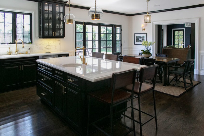 Kitchen with black cabinetry, marble island and brass fixtures